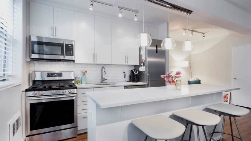Remodeled white kitchen with quartz counters, stainless steel appliances and an island with stools