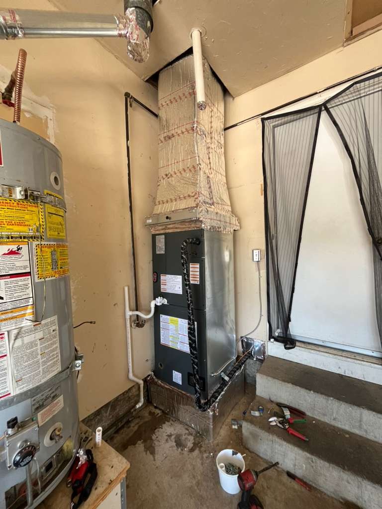 The new air handler in the Antioch garage corner, with its foil-wrapped plenum rising into the ceiling