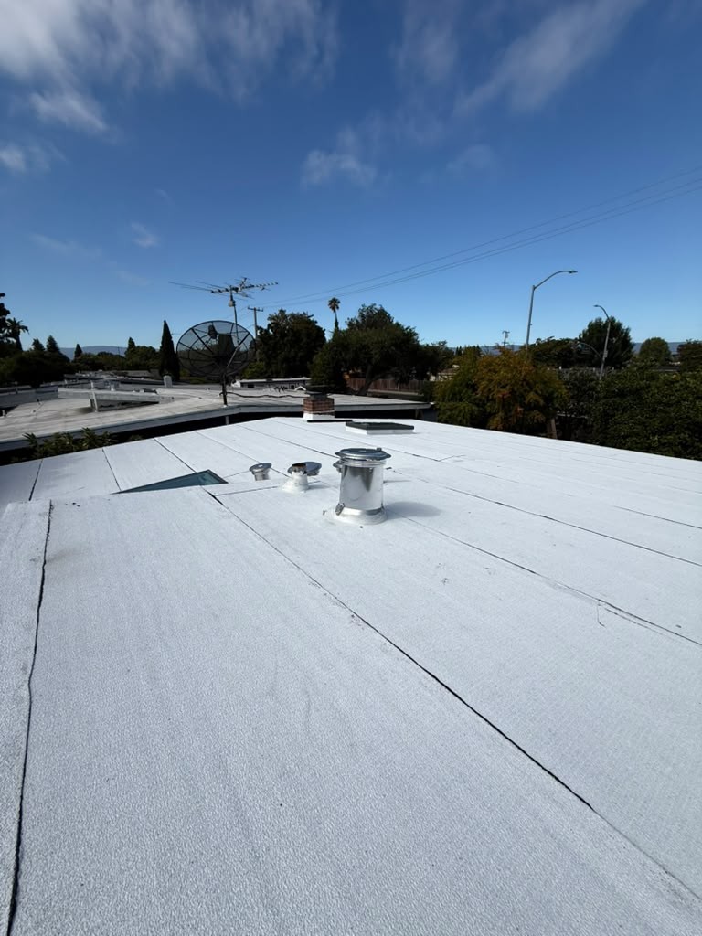 The new white torch-applied flat roof on the East Palo Alto house, with lapped seams and new metal vent stacks