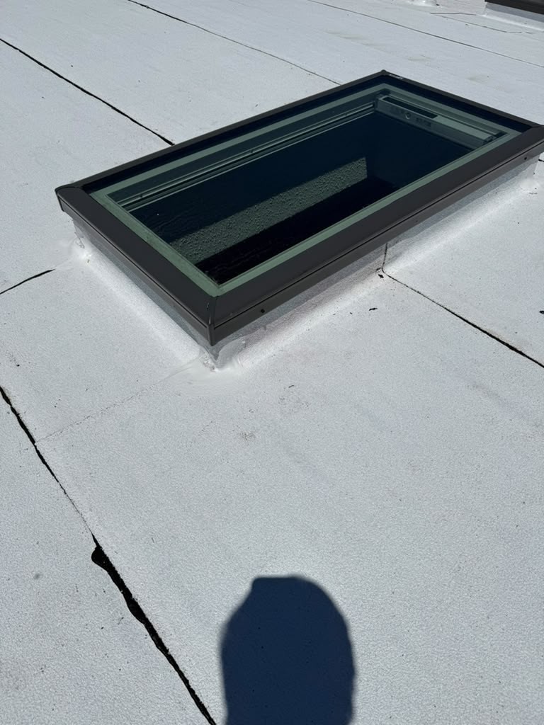 Close view of a new skylight curb sealed into the white roof membrane