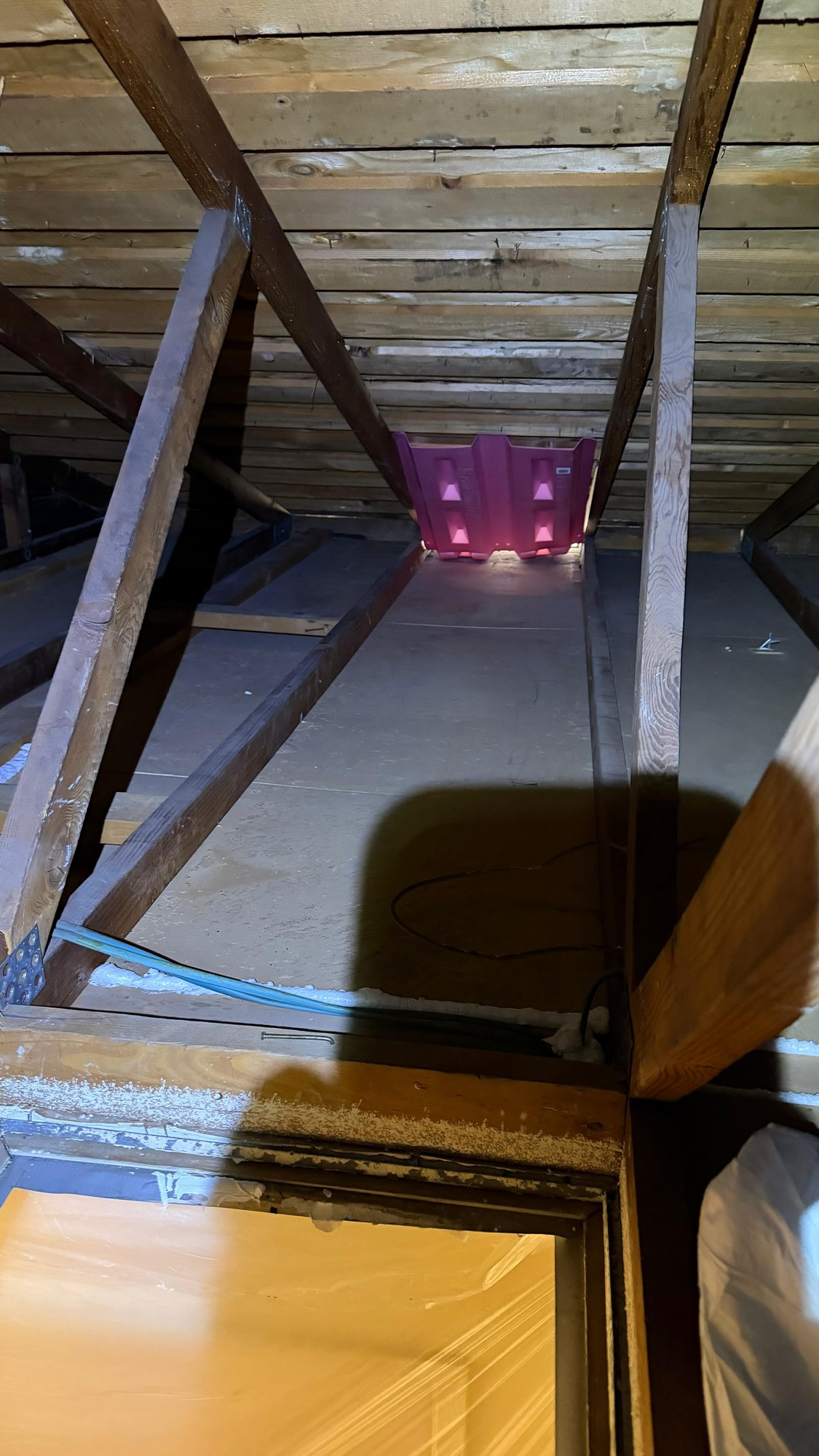 The emptied attic floor looking toward the eave, with a new pink baffle at the vent