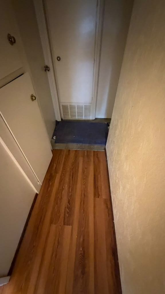 New wood-look plank flooring running down a hallway to closet doors in the San Diego house
