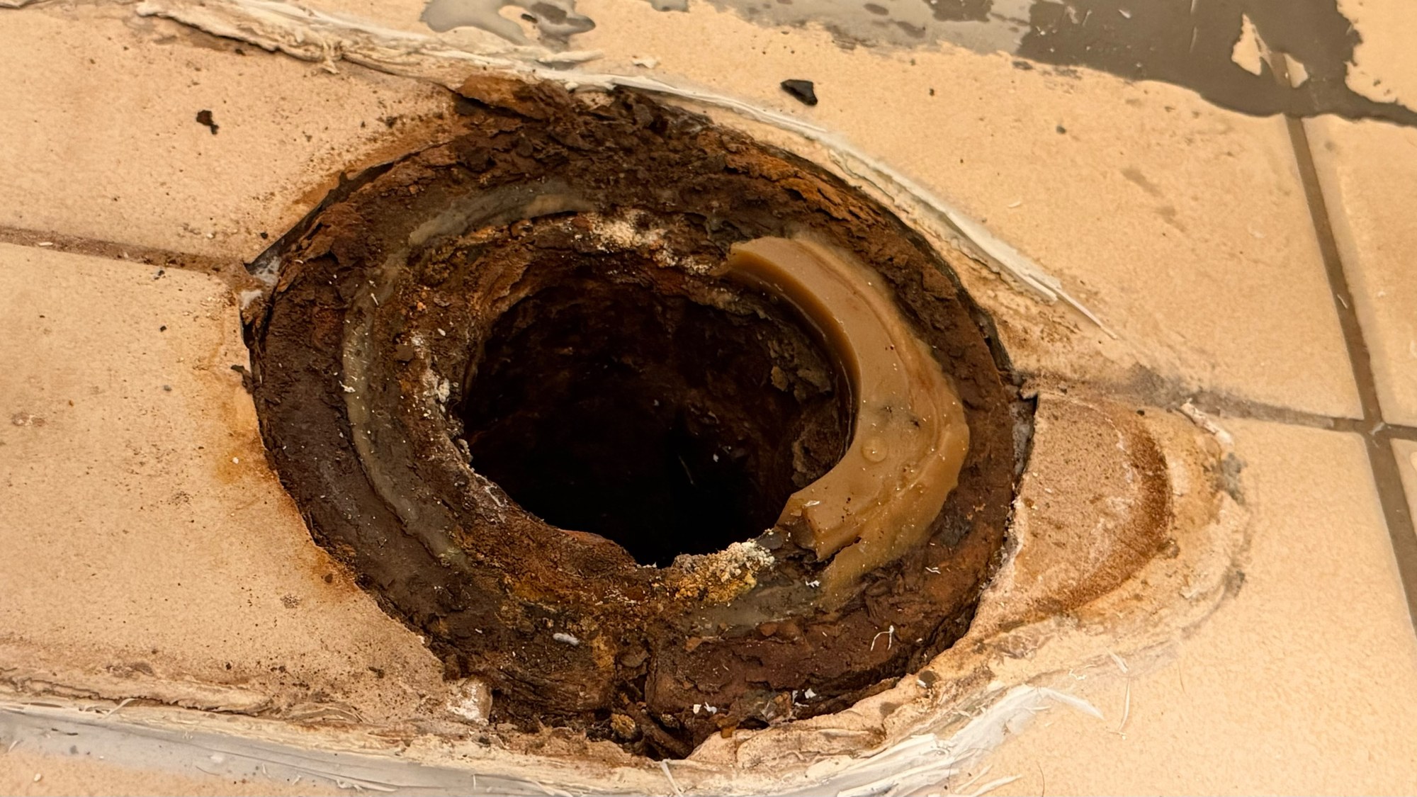 Close-up of the toilet flange on the bathroom tile after the toilet was lifted