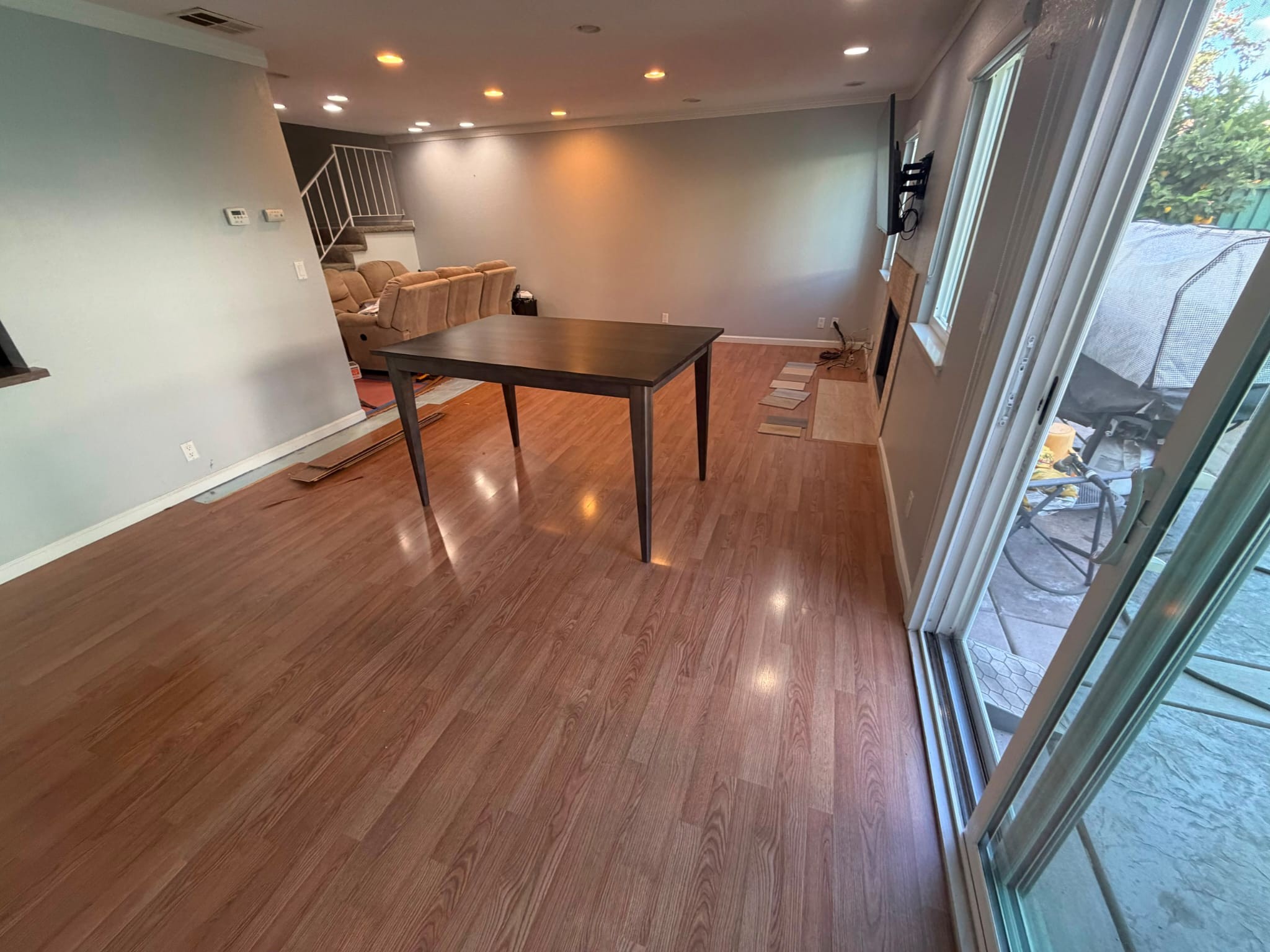 The San Jose living room on its glossy laminate floor, dining table in the middle and plank samples by the fireplace