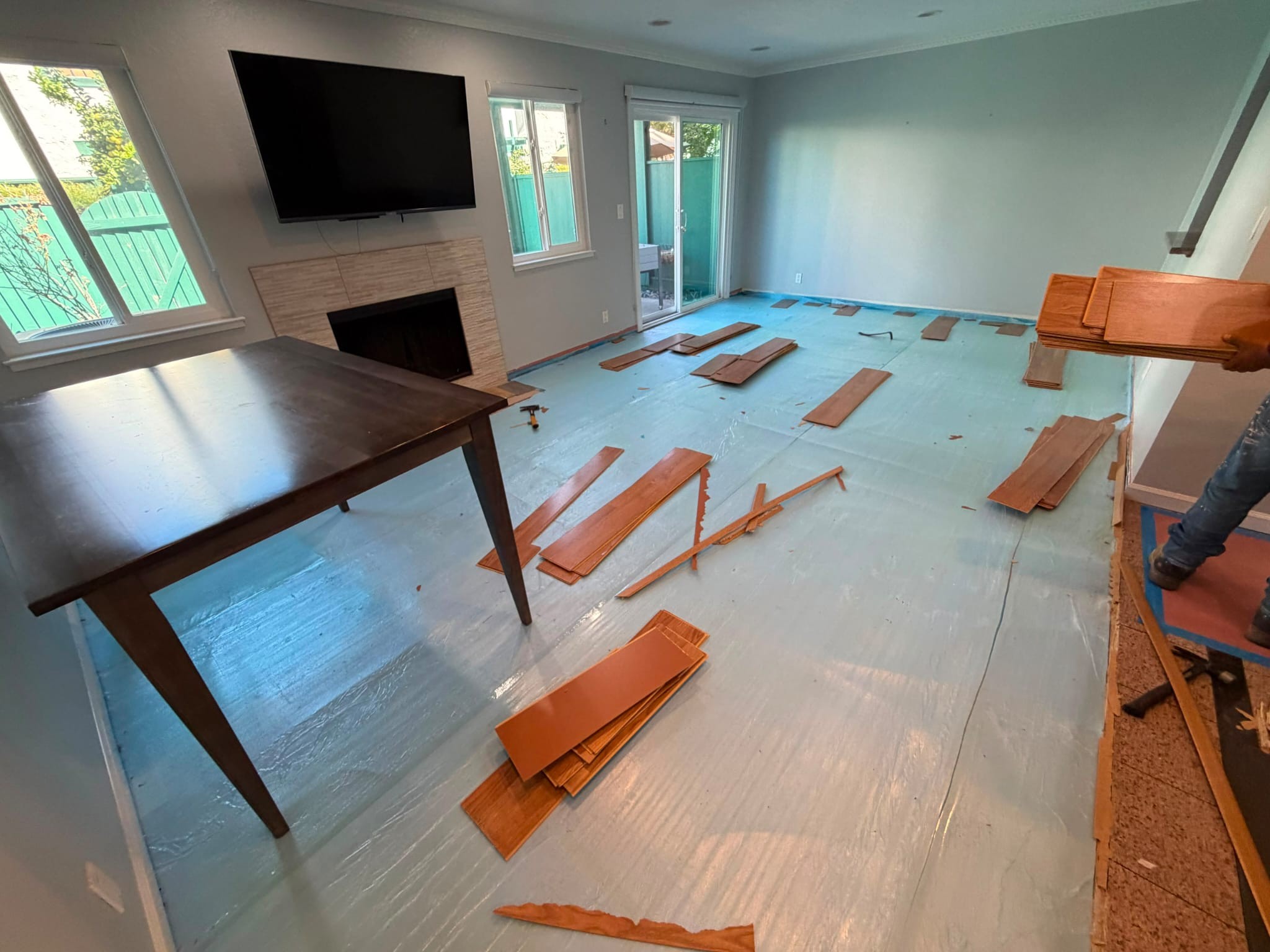 Laminate boards pulled up and scattered across the San Jose living room
