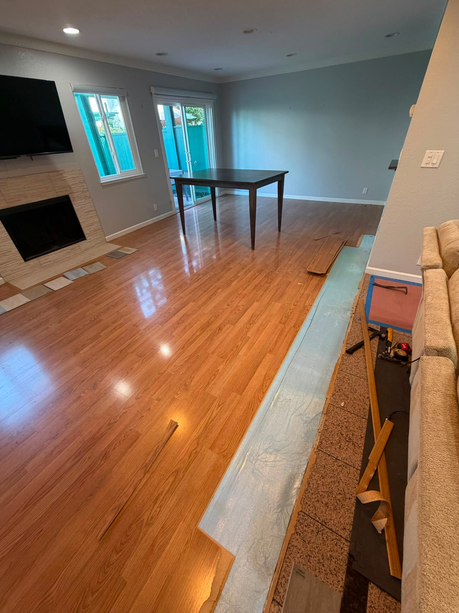 The first strip of laminate lifted along one wall of the San Jose living room